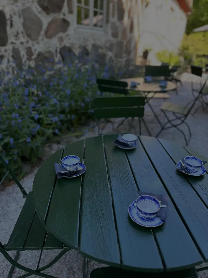 Kaffekoppar på ett grönt runt bord vid en stenmur
